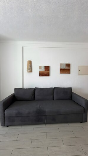 A modern living room with a grey sofa, white walls, and three abstract paintings. - Apartment 'Cozy  in Montechoro' with Balcony, Wi-Fi and Air Conditioning (Albufeira)