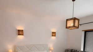 Een slaapkamer met een bed, nachtkastjes, een bank en een hanglamp.