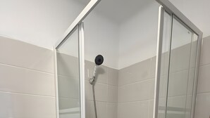 Een badkamer met een douchecabine, toilet en een blauwe badmat.