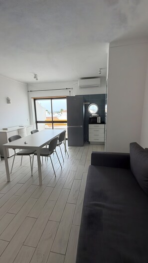 A modern kitchen with a built-in microwave, a refrigerator, and a window overlooking a cityscape. - Apartment 'Cozy  in Montechoro' with Balcony, Wi-Fi and Air Conditioning (Albufeira)