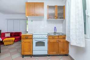 Een kleine keuken met een fornuis, spoelbak en houten kastjes.