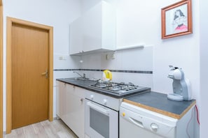Eine kleine Küche mit Herd, Backofen und Kaffeemaschine.