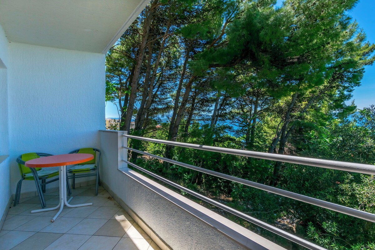 Ein Balkon mit Tisch und Stühlen mit Blick auf ein bewaldetes Gebiet.