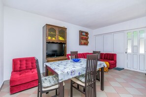 Ein Essbereich mit Tisch, Stühlen, einer Couch, einem Schrank und einem Fernseher.
