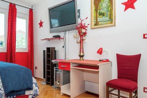 A bedroom with a bed, a desk, a chair, a TV, and a window with curtains. - Apartment Near City Center (Split)