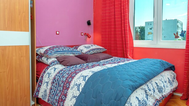A bedroom with a bed, a window, and a view of buildings outside. - Apartment Near City Center (Split)