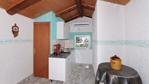 Uma cozinha compacta com teto de madeira, uma mesa pequena com uma panela e uma janela com vista.