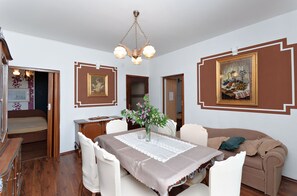 A dining area with a table set for four, a sofa, and a bed in the background. - Apartments and Room Gulic (Rab)
