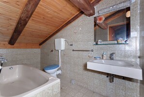 A bathroom with a bathtub, toilet, sink, and mirror. - Apartments and Room Gulic (Rab)