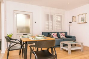 Uma sala de estar moderna com uma mesa de jantar, cadeiras, um sofá e uma mesa de centro.
