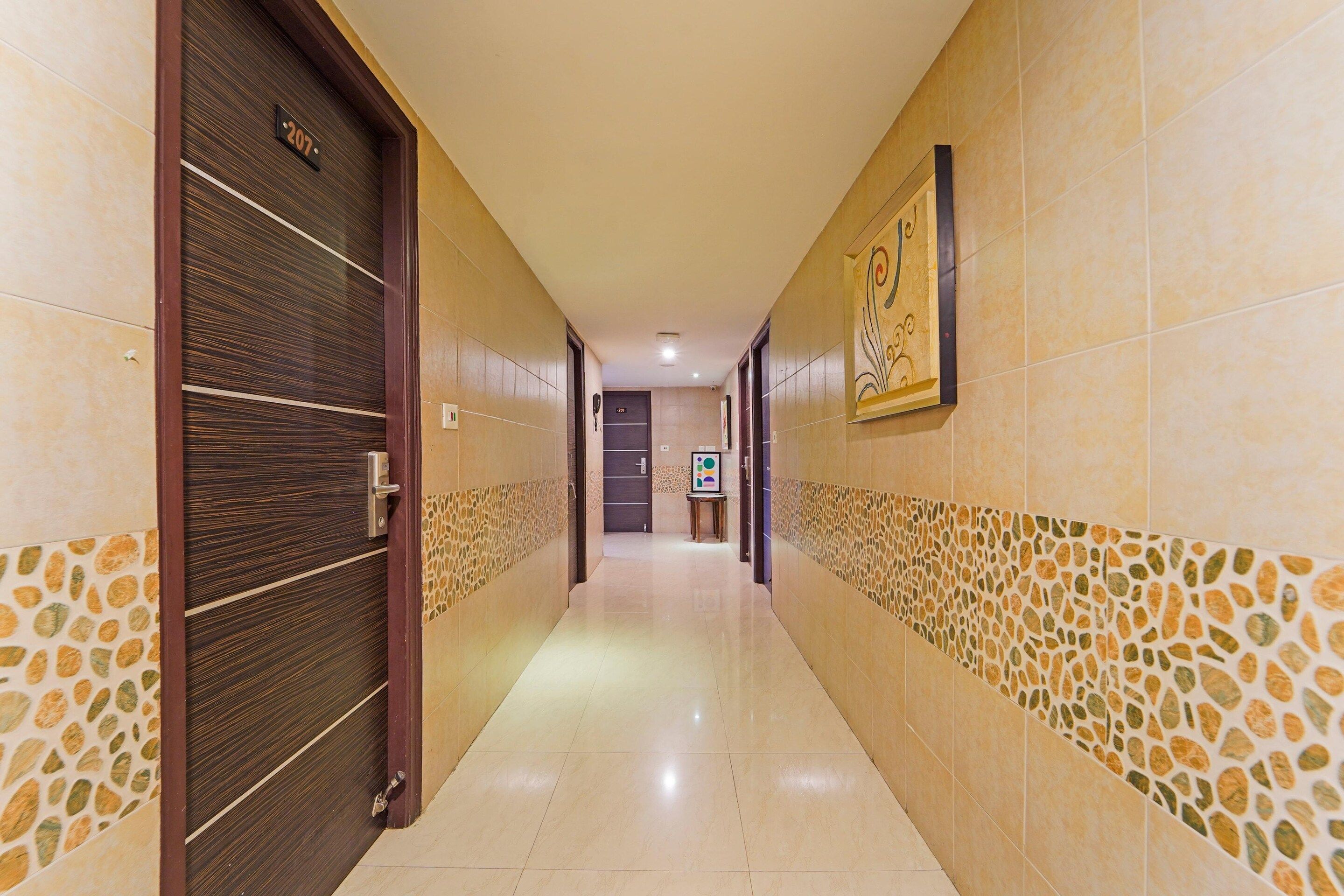 A hotel corridor with a tiled floor, a door with a number plate, and a framed artwork on the wall.