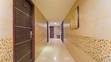 A hotel corridor with a tiled floor, a door with a number plate, and a framed artwork on the wall.