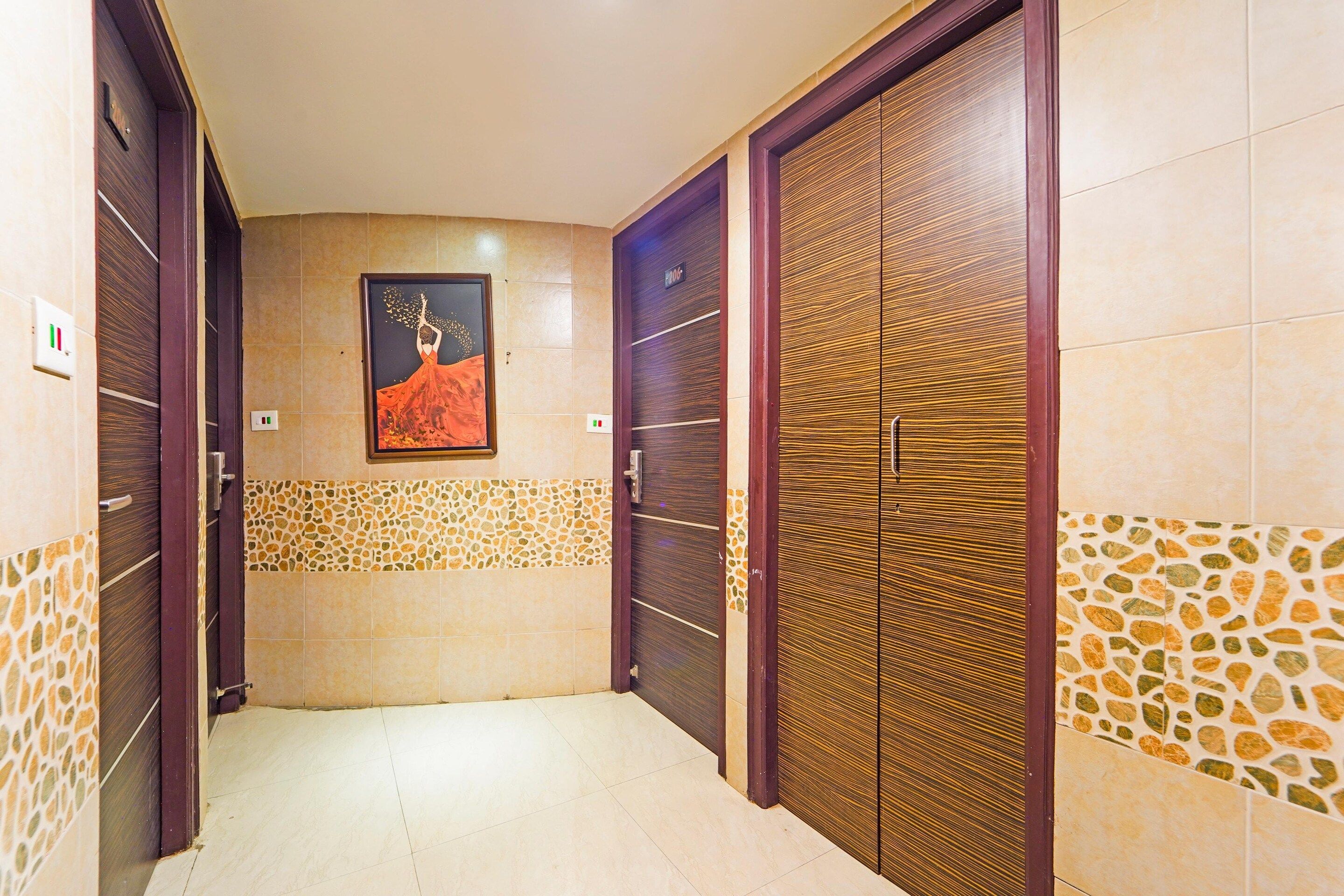 A hallway with two wooden doors, a tiled wall with a mosaic pattern, and a framed picture on the wall.