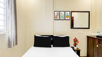 A hotel room with a bed, a nightstand, a mirror, and wall art.