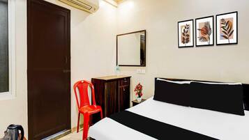 A hotel room with a bed, a desk, a chair, a mirror, and wall art.