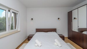 A bedroom with a large bed, bedside tables, a wardrobe, and a window. - House Melani (Zminj)