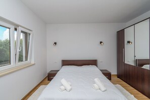 Ein Schlafzimmer mit einem großen Bett, Nachttischen, einem Kleiderschrank und einem Fenster.