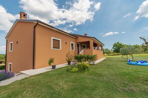 A two-story house with a balcony, a small garden, and a blue inflatable pool. - House Melani (Zminj)