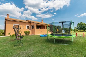 Ein Haus mit einem grünen Trampolin und einem kleinen Pool im Garten.