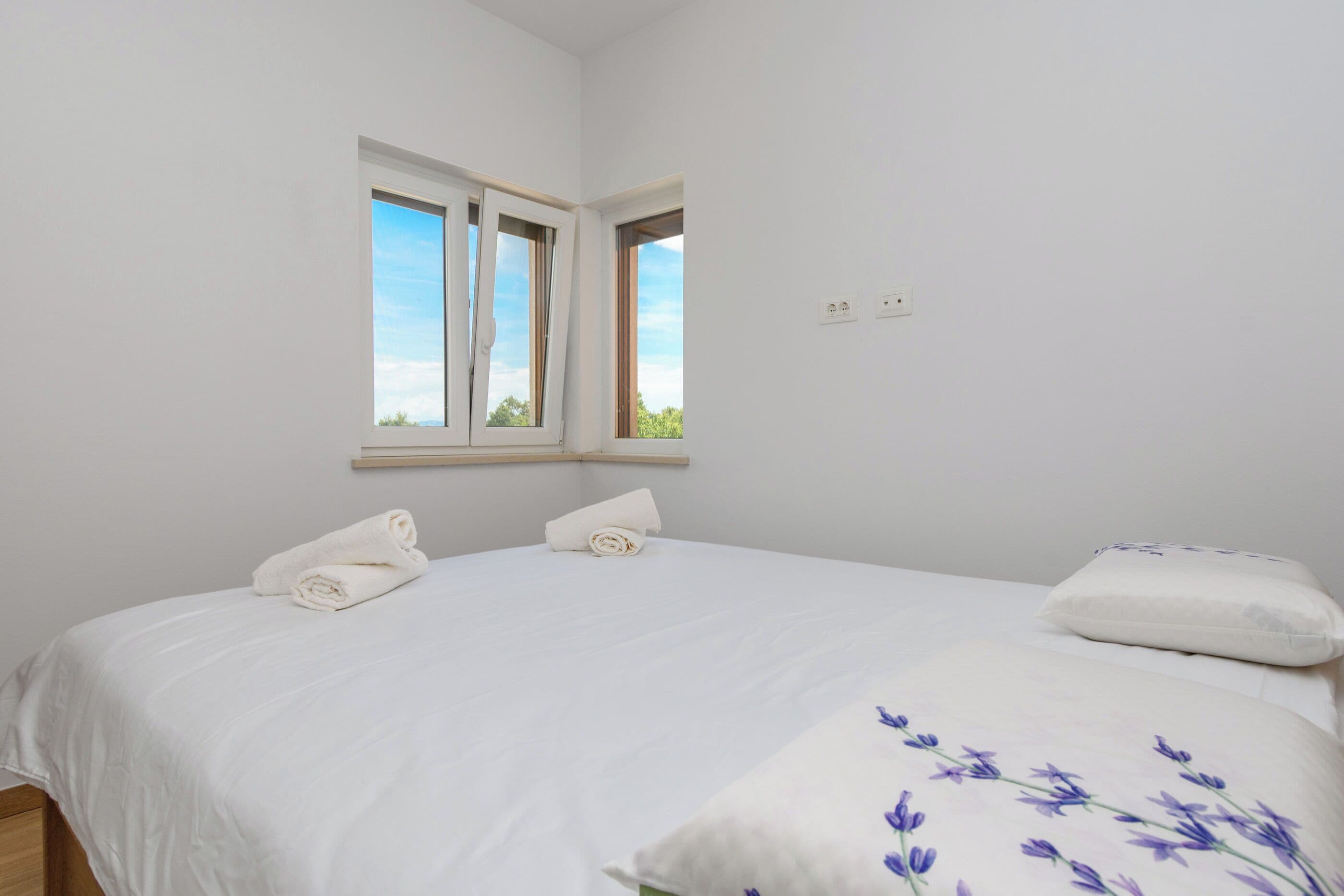 Una camera da letto con un letto, due cuscini, una finestra e una presa elettrica.