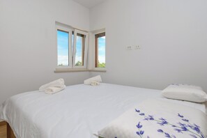 A bedroom with a bed, two pillows, a window, and a wall socket. - House Melani (Zminj)