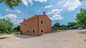 A two-story house with a gravel driveway and a car parked in the background. - House Melani (Zminj)