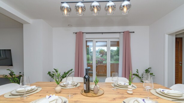 A dining room with a wooden table set for four, a bottle, and glasses. - House Melani (Zminj)