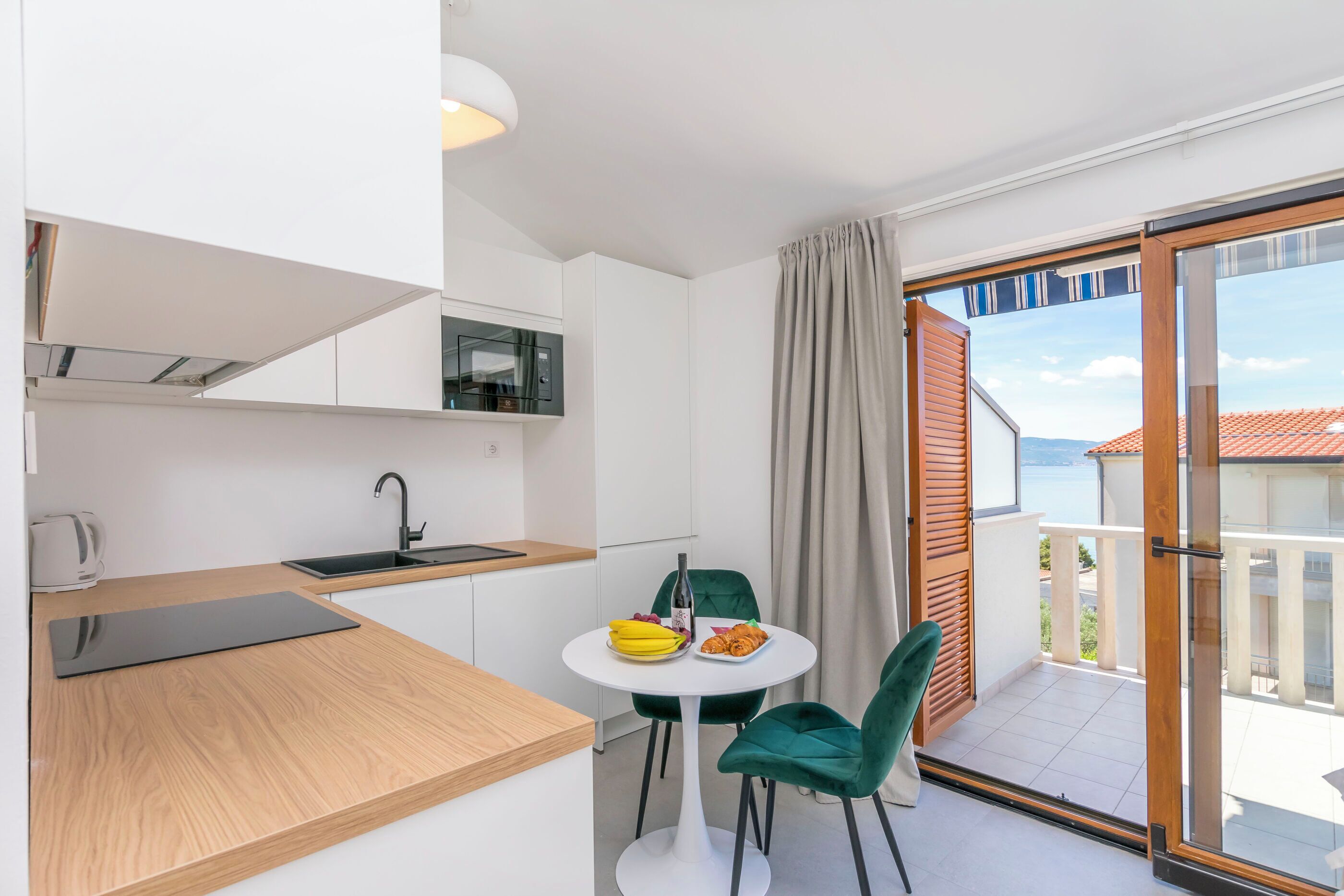 Una cocina moderna con comedor, vista al mar y un balcón con puerta corredera.