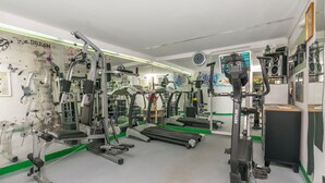Ein Fitnessraum mit verschiedenen Trainingsgeräten, Laufband und einer Spiegelwand.