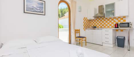 Ein Hotelzimmer mit Bett, Schreibtisch, Stuhl, Mikrowelle, Mülleimer und Blick ins Freie.