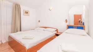 Ein Hotelzimmer mit einem hölzernen Bett, einem kleinen Nachttisch, einem Spiegel und einem Kleiderschrank.
