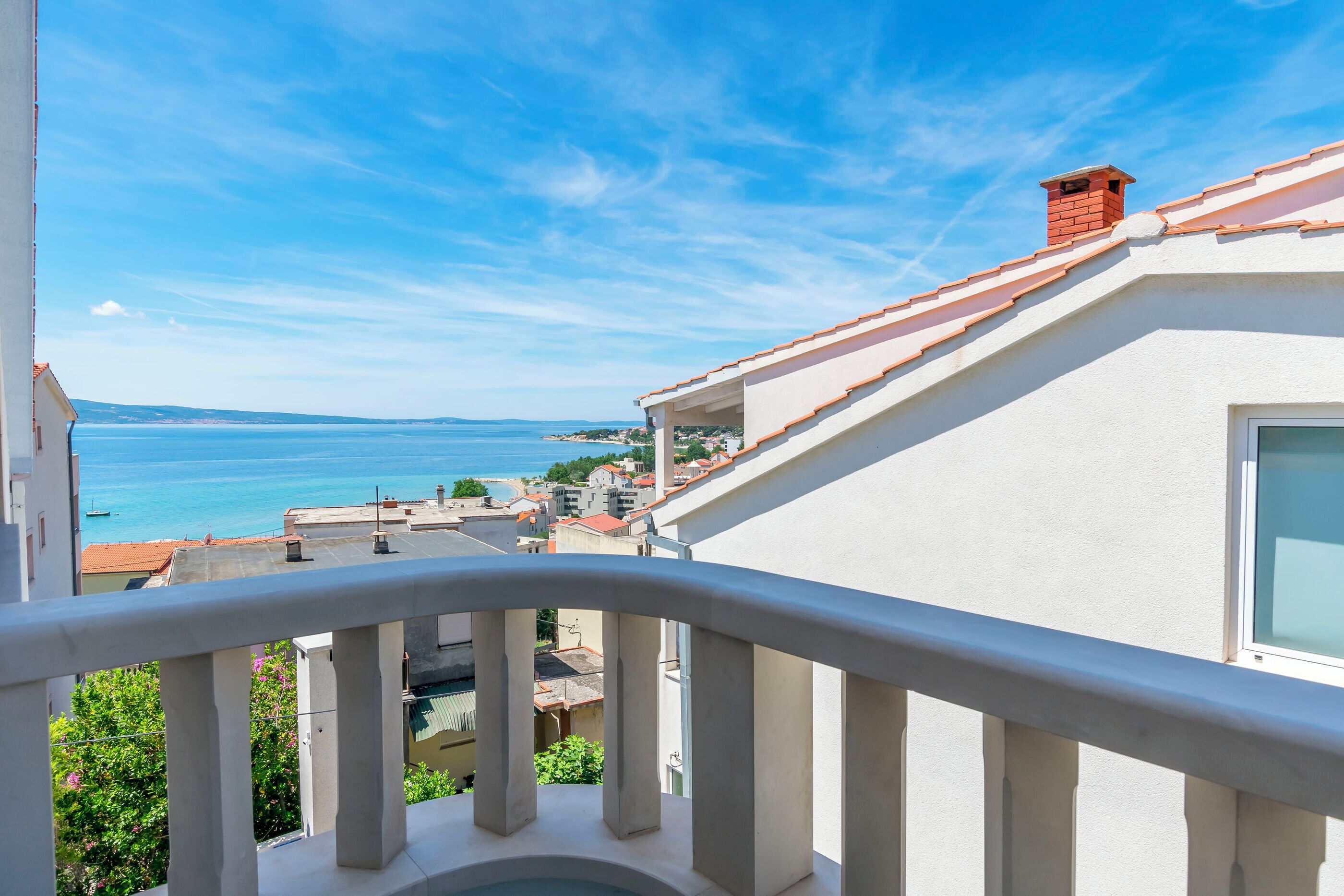 A balcony with a view of the sea and buildings.