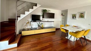 Eine moderne Küche mit eingebautem Ofen und Mikrowelle, ein Essbereich mit gelben Stühlen und eine Treppe, die zu einer weiteren Ebene führt.