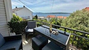 Ein Balkon mit Tisch und Stühlen, mit Blick auf ein Gewässer und Gebäude.