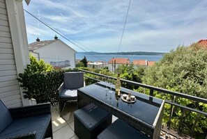 Ein Balkon mit Tisch und Stühlen, mit Blick auf ein Gewässer und Gebäude.
