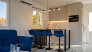 Uma cozinha moderna com banquetas, uma mesa de jantar com copos de vinho e um sofá azul.
