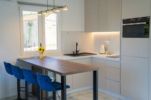 Eine moderne Küche mit einer Holzinsel, Barhocker, einem Backofen und einem Fenster mit Blick auf ein Steinhaus.