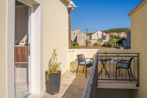 Ein Balkon mit Tisch und Stühlen, einem Blumentopf und Blick auf Häuser im Hintergrund.