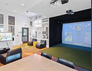 A modern lounge area with a large screen for presentations, comfortable seating, and a projector. - Disney Villa | Theater, Pool & Game Room Sleeps 22 (Kissimmee)