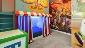 Una stanza con una biglietteria, un letto con tende a righe e un murale con personaggi animati.