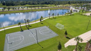 Un campo da basket all'aperto con specchio d'acqua e alberi sullo sfondo.