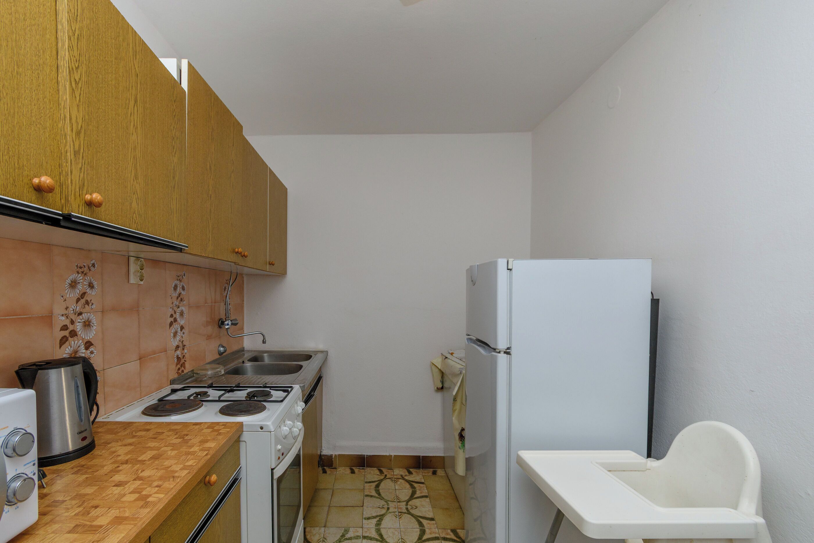 A compact kitchen with wooden cabinets, a gas stove, a sink, and a white refrigerator.