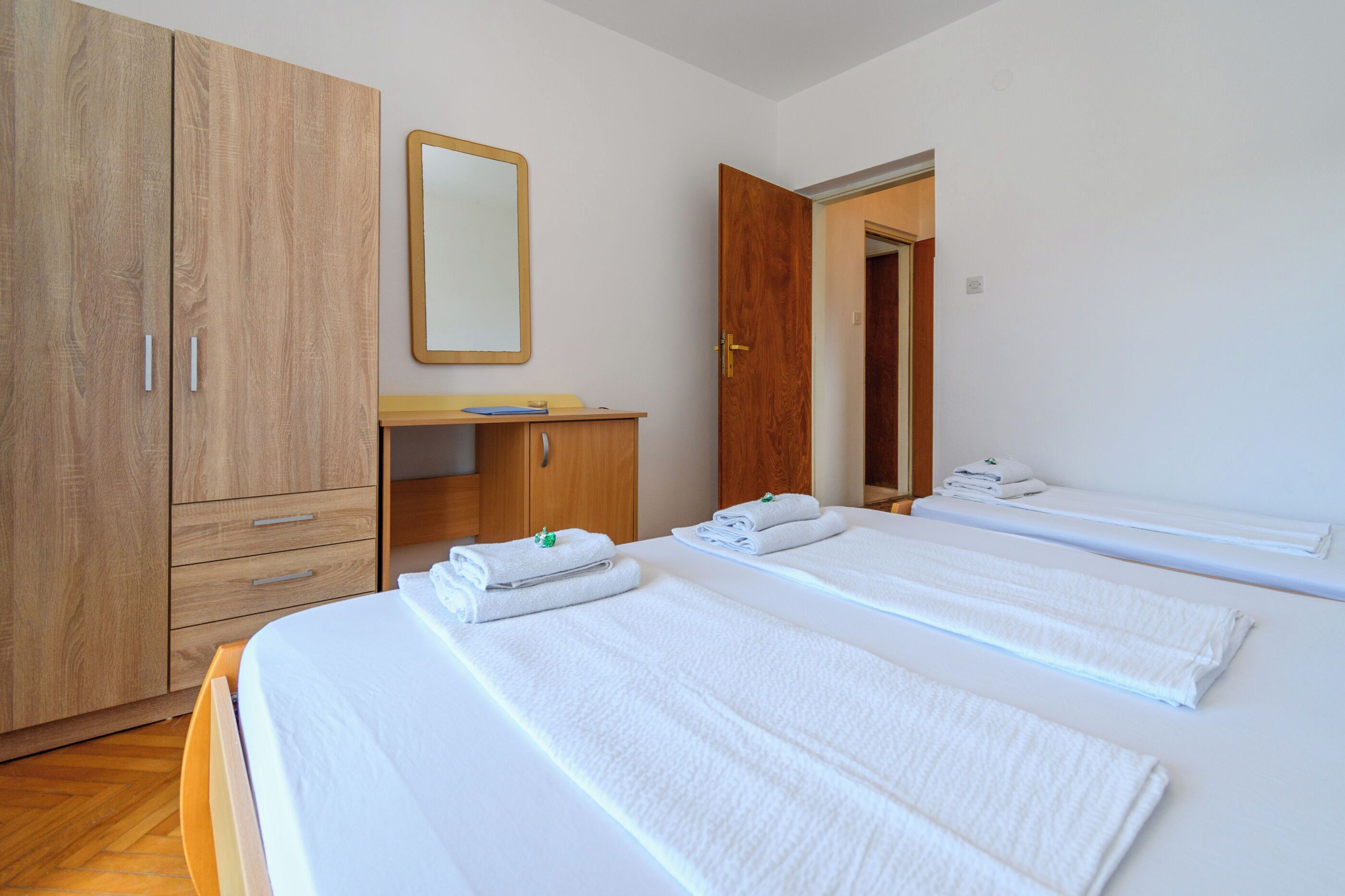 Ein Hotelzimmer mit zwei Betten, einem Holzschrank, einem Schreibtisch und einem Spiegel.