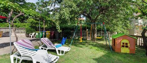 A playground with swings, a slide, and a small playhouse.