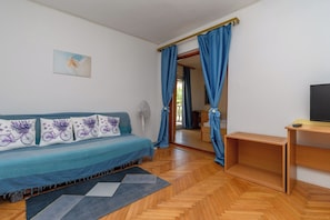 A room with a sofa, a TV, a wooden desk, and a mirror. - Rooms Borka (Lopar)