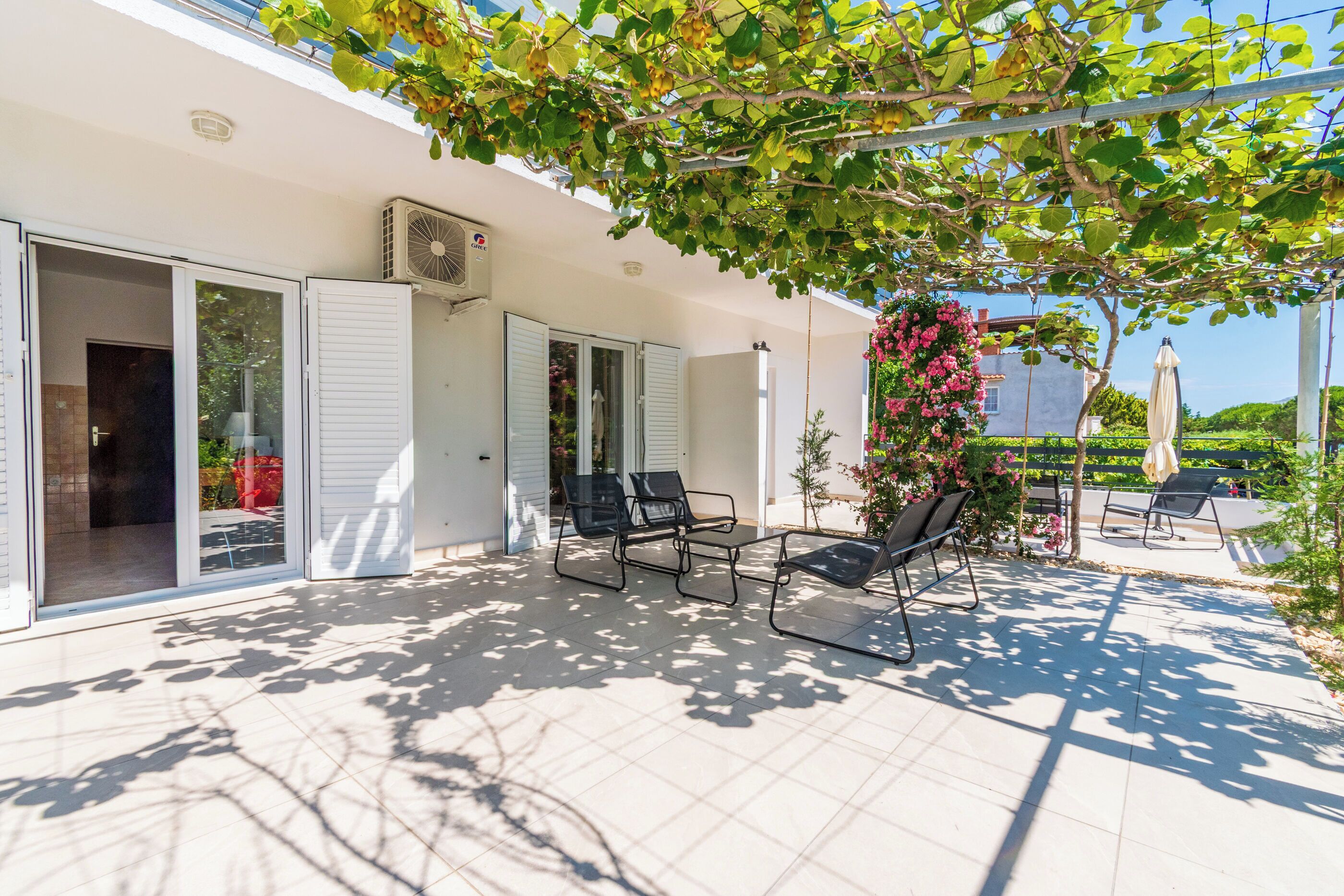 A covered outdoor patio with sliding glass doors, a ceiling fan, and outdoor furniture.