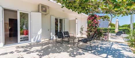 A covered outdoor patio with sliding glass doors, a ceiling fan, and outdoor furniture.