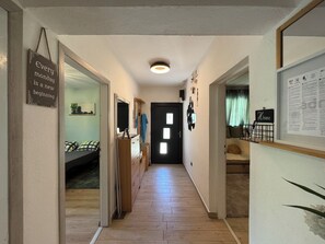 A hallway with a bed, dresser, and a door leading to another room. - Apartment Pine and Salt (Vinodol)