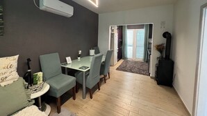 Una cocina moderna con estufa integrada, una zona de comedor con mesa y sillas, y un pasillo que lleva a una puerta.