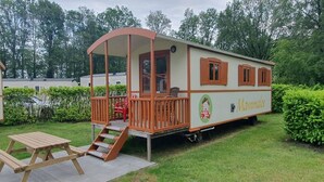 A mobile home with a covered porch, a picnic table, and a small deck. - Verblijf in een unieke Pipowagen | De Otterberg (Wijster)